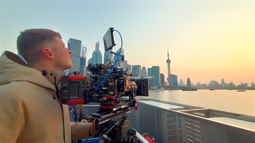 Camera crew working outdoors in Shanghai with a city skyline in the background